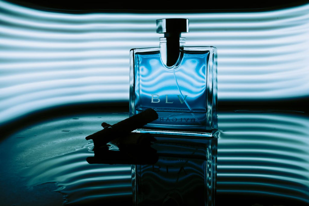 Rectangular blue fragrance bottle against wavy blue light stripes with reflection