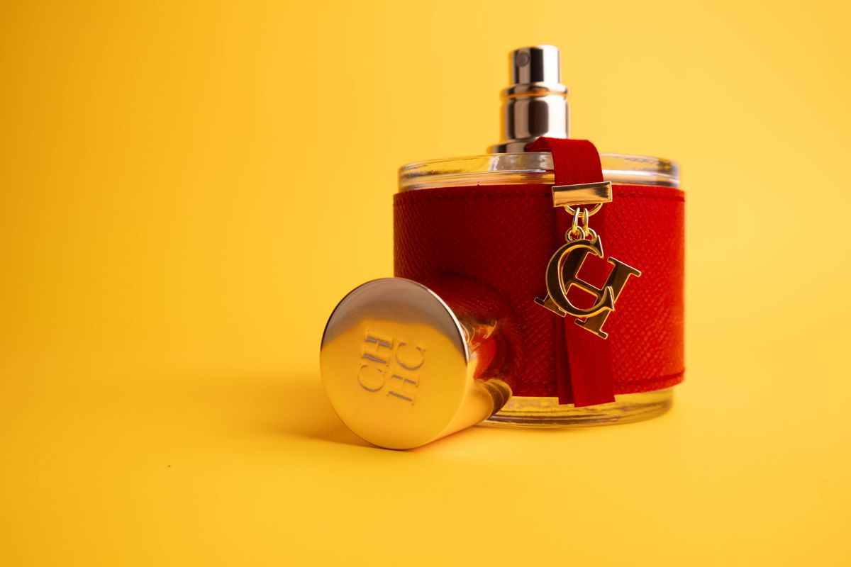 Red perfume bottle with gold detailing on yellow backdrop