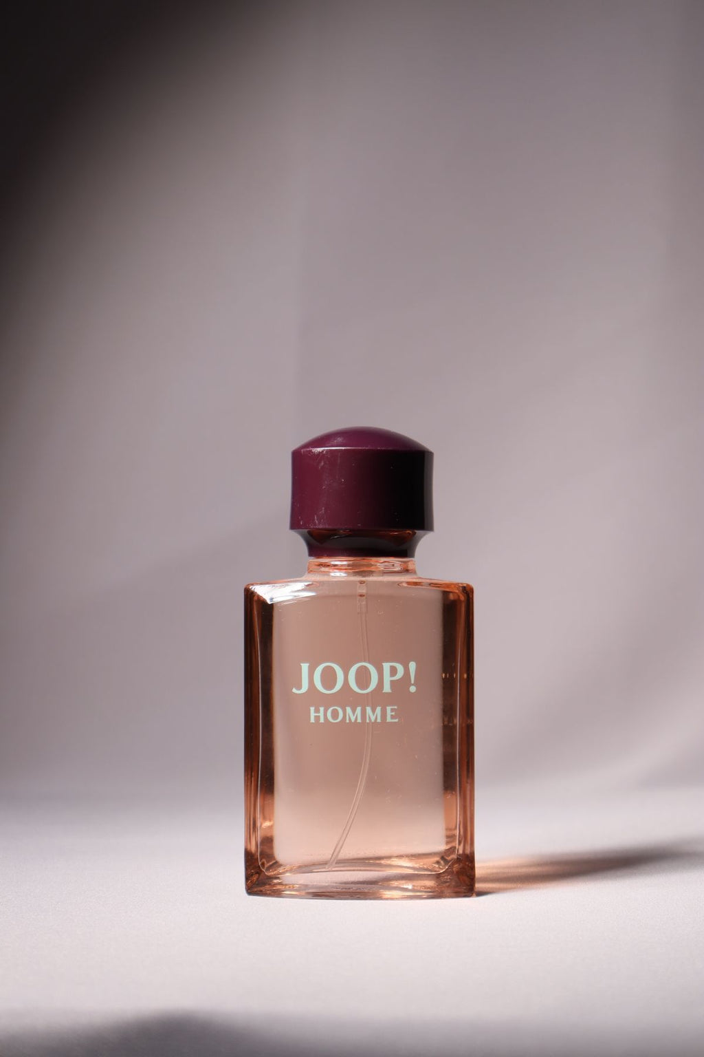 Joop! Homme perfume bottle with burgundy cap on a neutral background