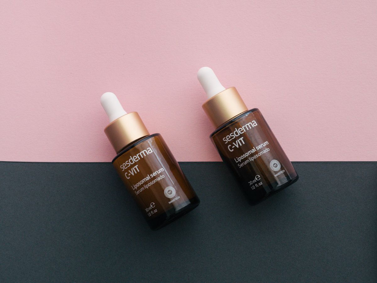 Two serum bottles with pink and black backdrop