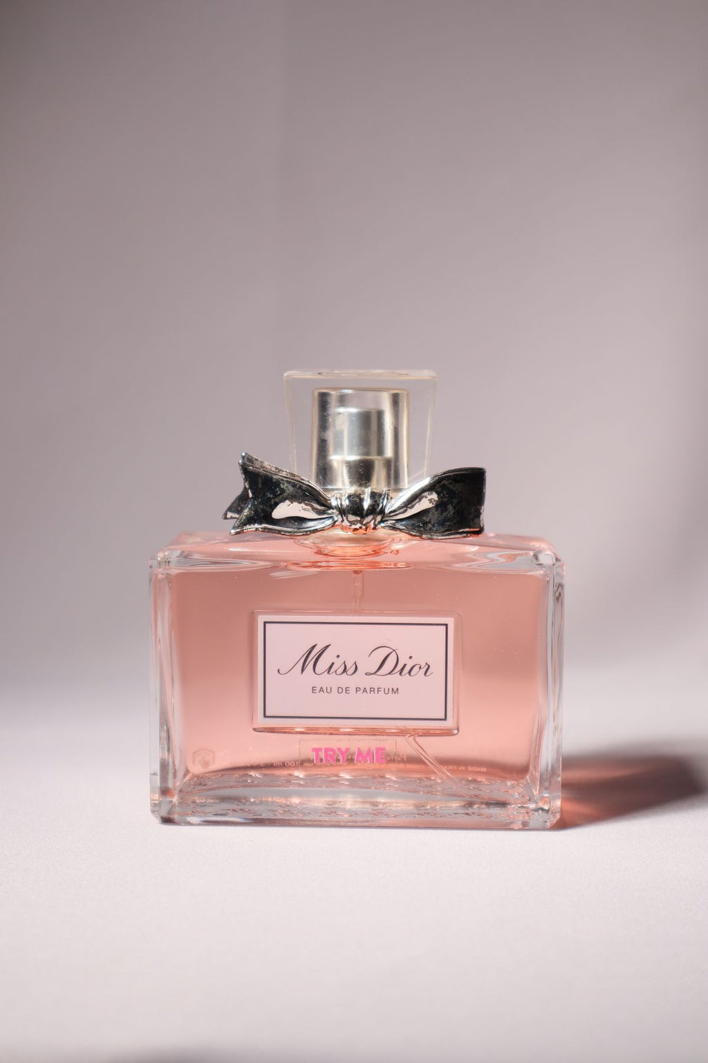 Miss Dior pink perfume bottle with silver bow on a light backdrop