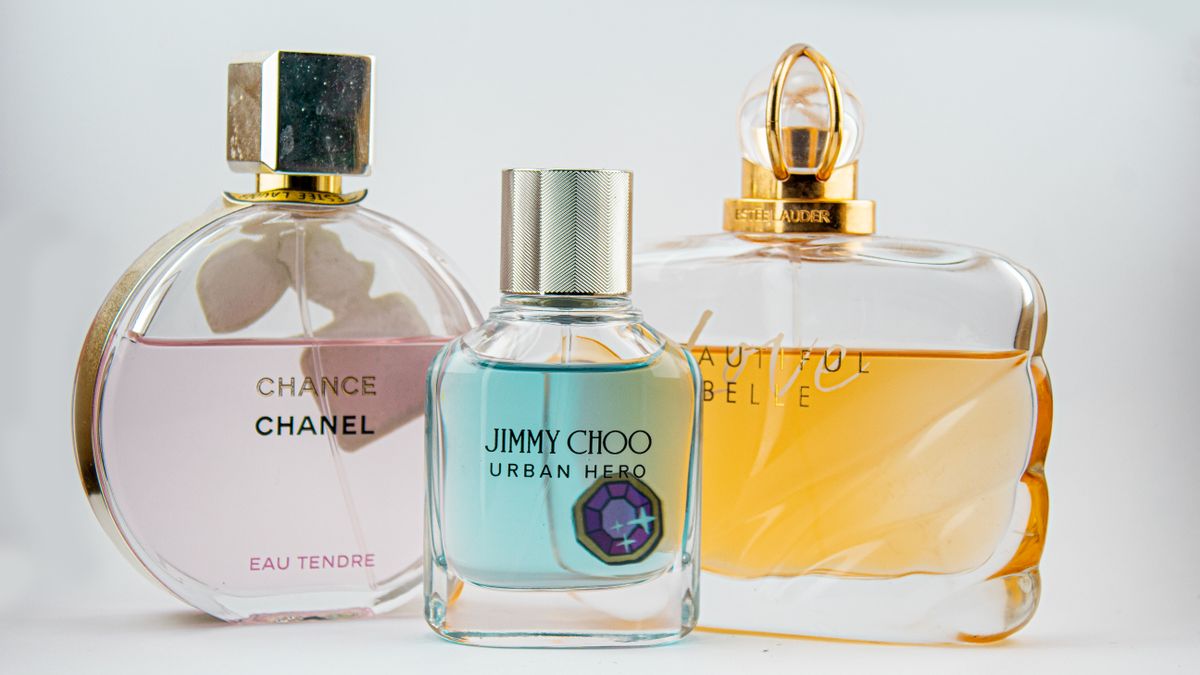 Three perfume bottles with pink, blue, and amber liquids on a light background